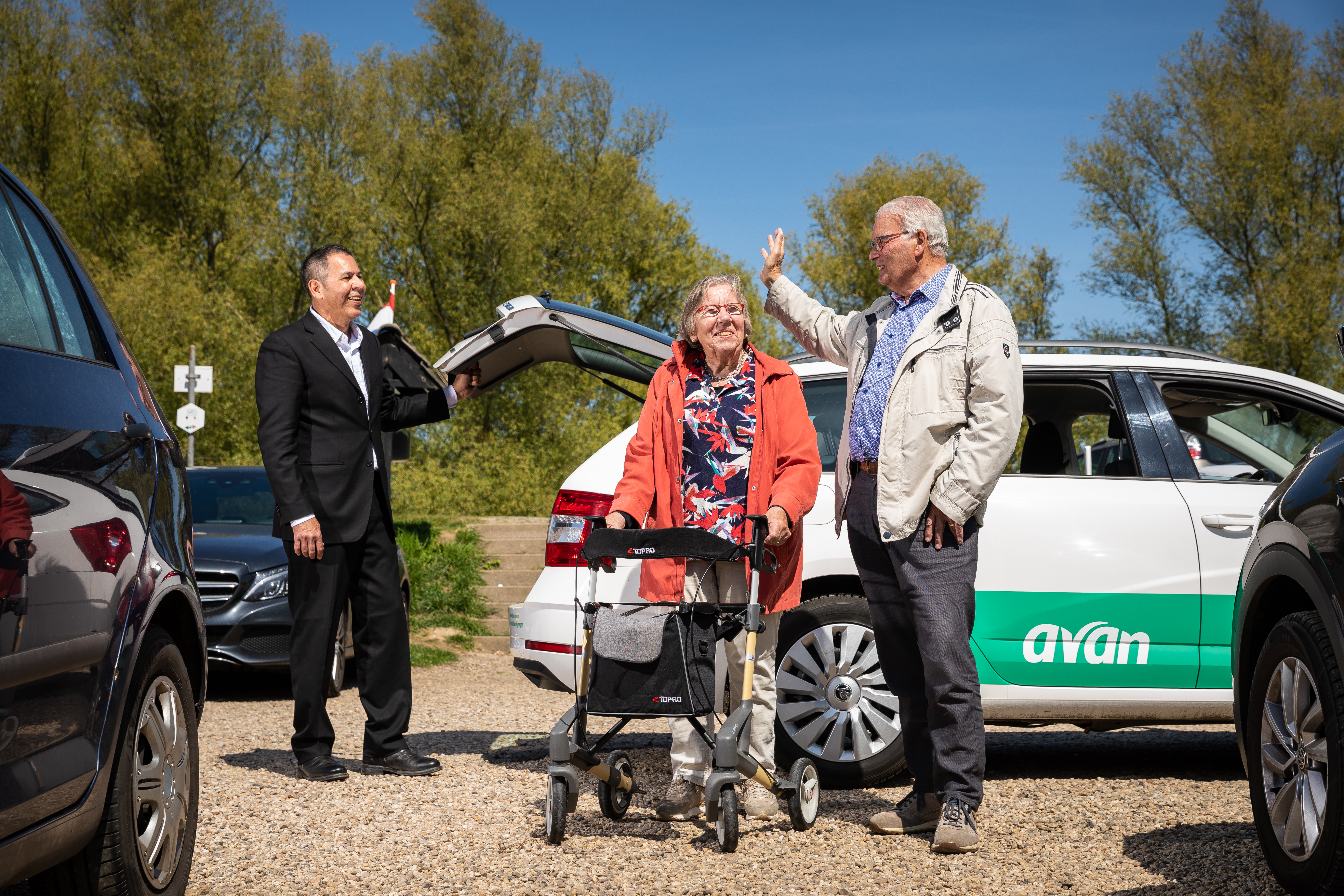 Man en vrouw lopen weg bij de Avan taxi, terwijl ze zwaaien naar de chauffeur.